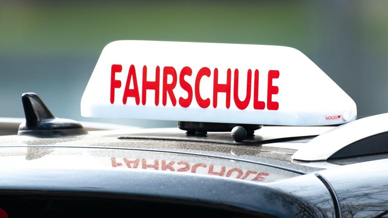 "Fahrschule"-Anzeige auf einem Autodach.