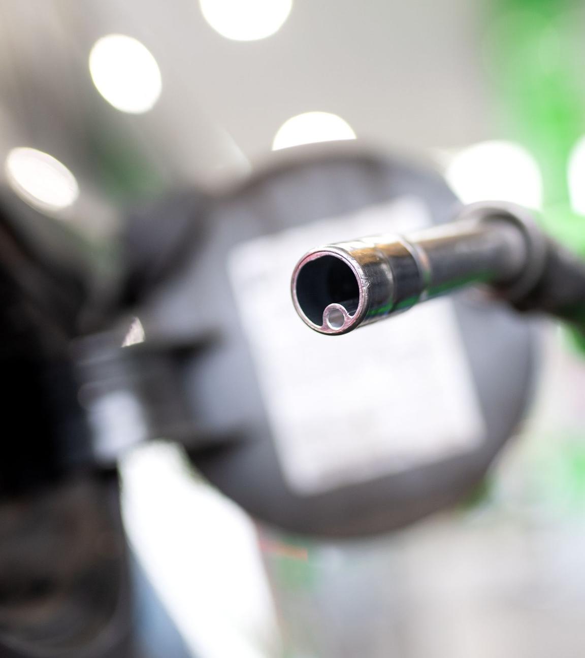 Frau hält an einer Tankstelle eine Zapfpistole. Symbolpolitik