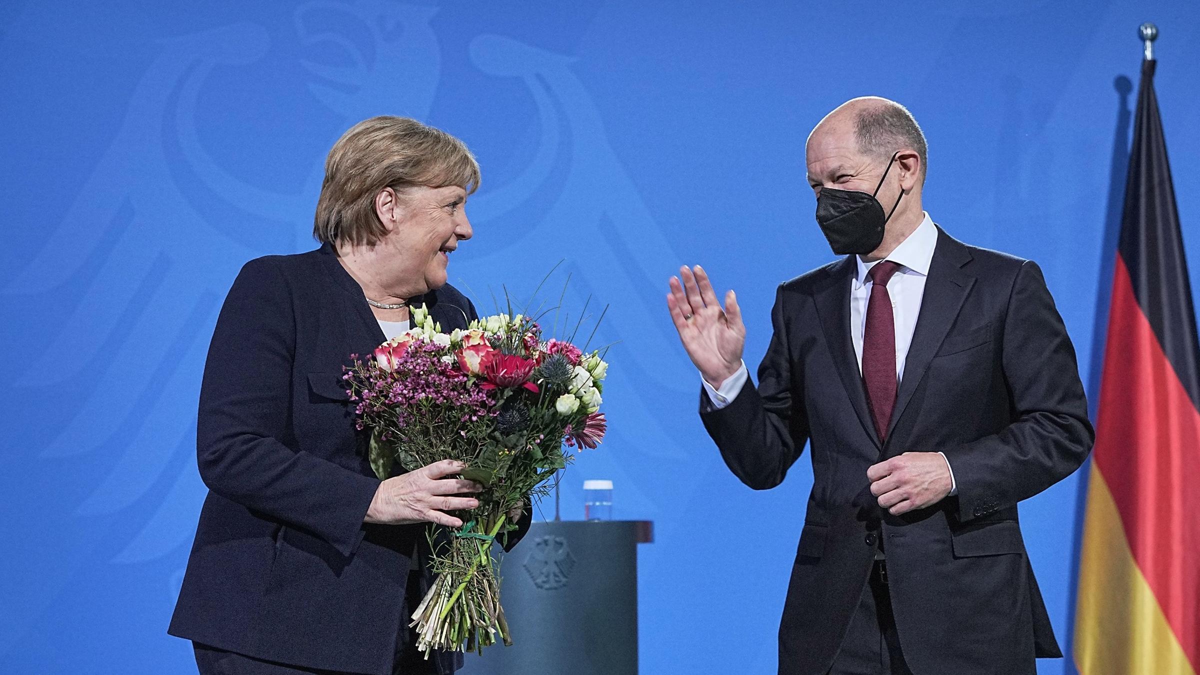Olaf Scholz (r.) übergibt im Kanzleramt Blumen an Angela Merkel.