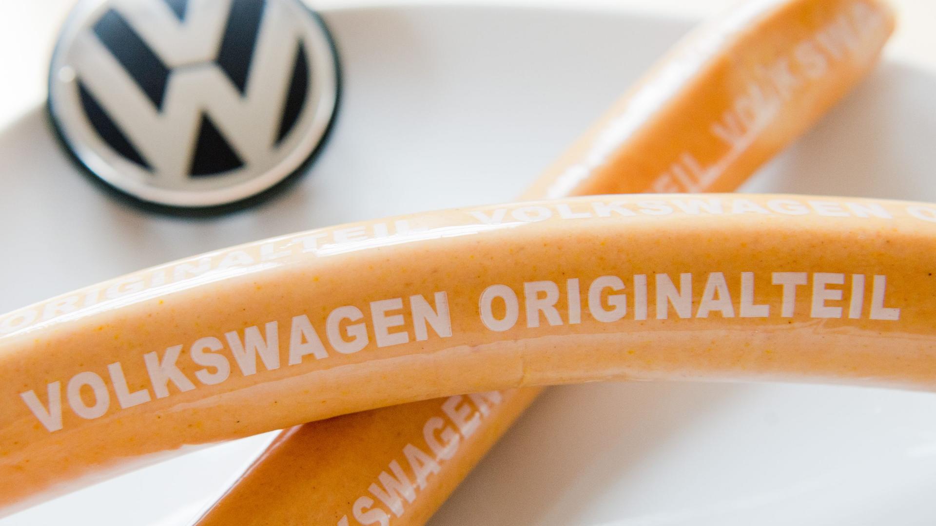 Zwei Currywürste liegen auf einem Teller mit VW-Logo. Archivbild