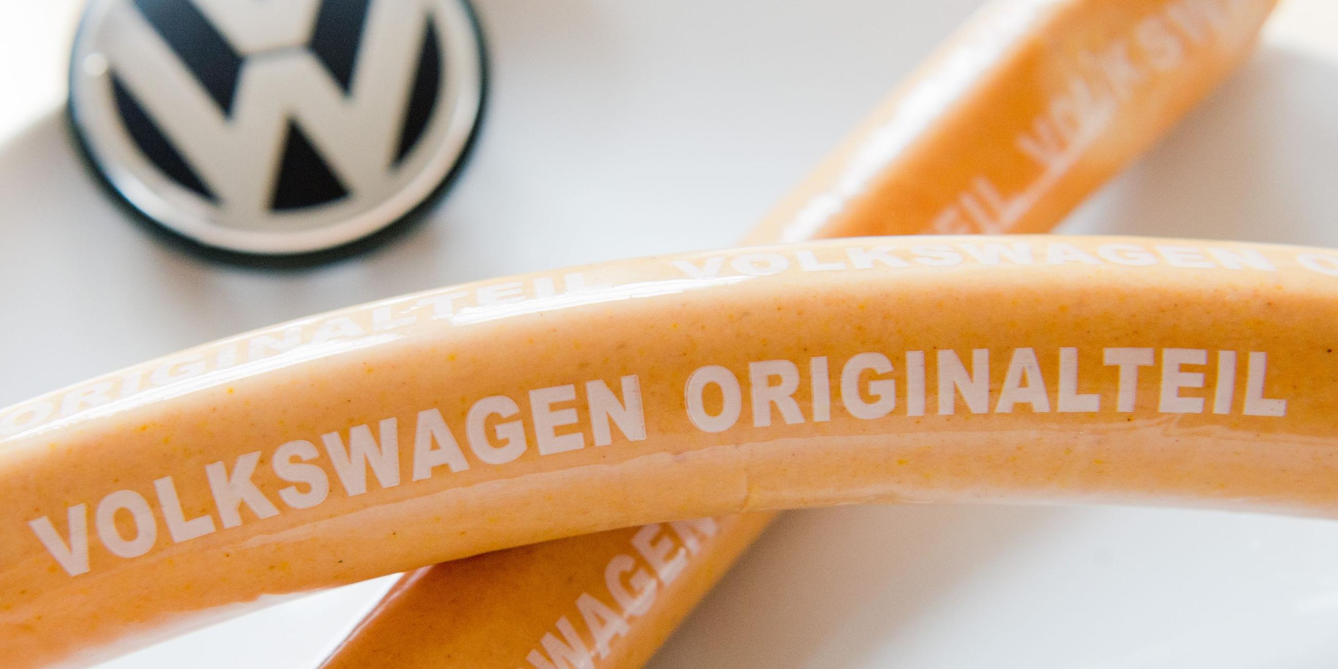 Zwei Currywürste liegen auf einem Teller mit VW-Logo. Archivbild