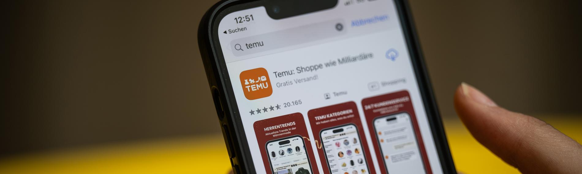 Eine Person hält ein Handy mit der App Temu in den Händen. 