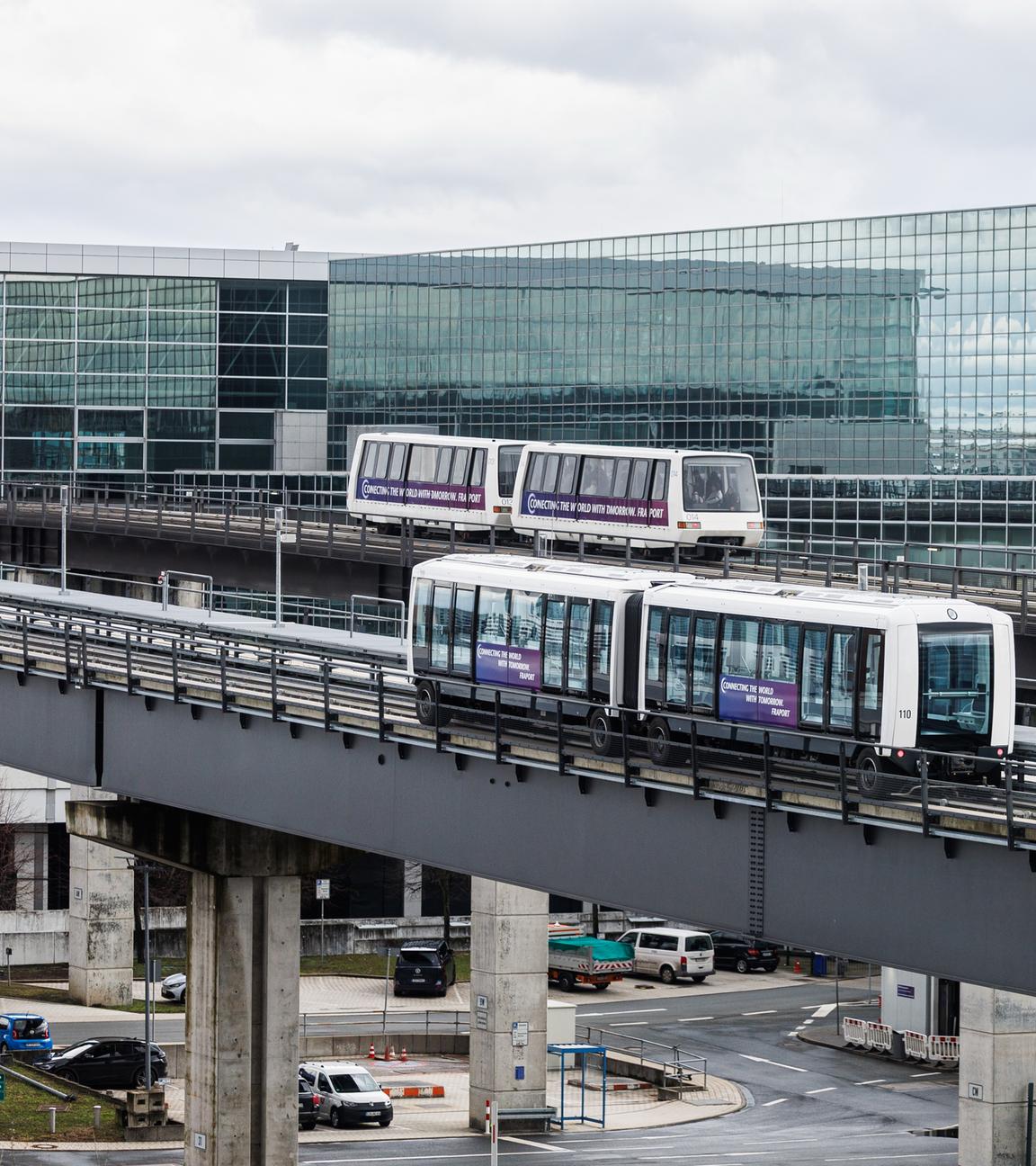 Eine neue Sky Line-Bahn fährt parallel zu einer alten Bahn am Frankfurter Flughafen. 