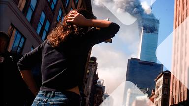 Eine Frau schaut von der Straße in die Höhe auf einen der brennenden Türme am 11. September 2001. 