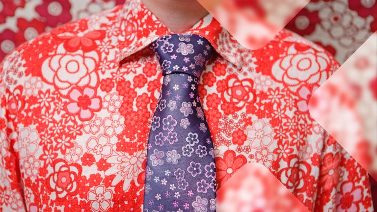 Ein rotes Hemd mit wildem Blumenmuster ist die Basis für eine lila Krawatte, ebenfalls mit Blumenmuster.