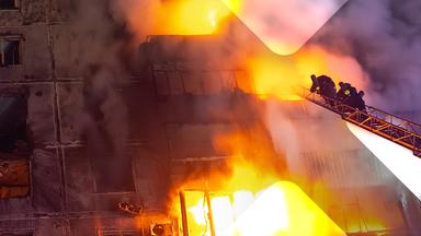 Ein brennendes Wohnhaus in der Ukraine, Feuerwehrleute auf einer Drehleiter.