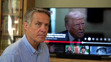 Terry Moran sitzt vor einem Bildschirm, auf dem Donald Trump zu sehen ist