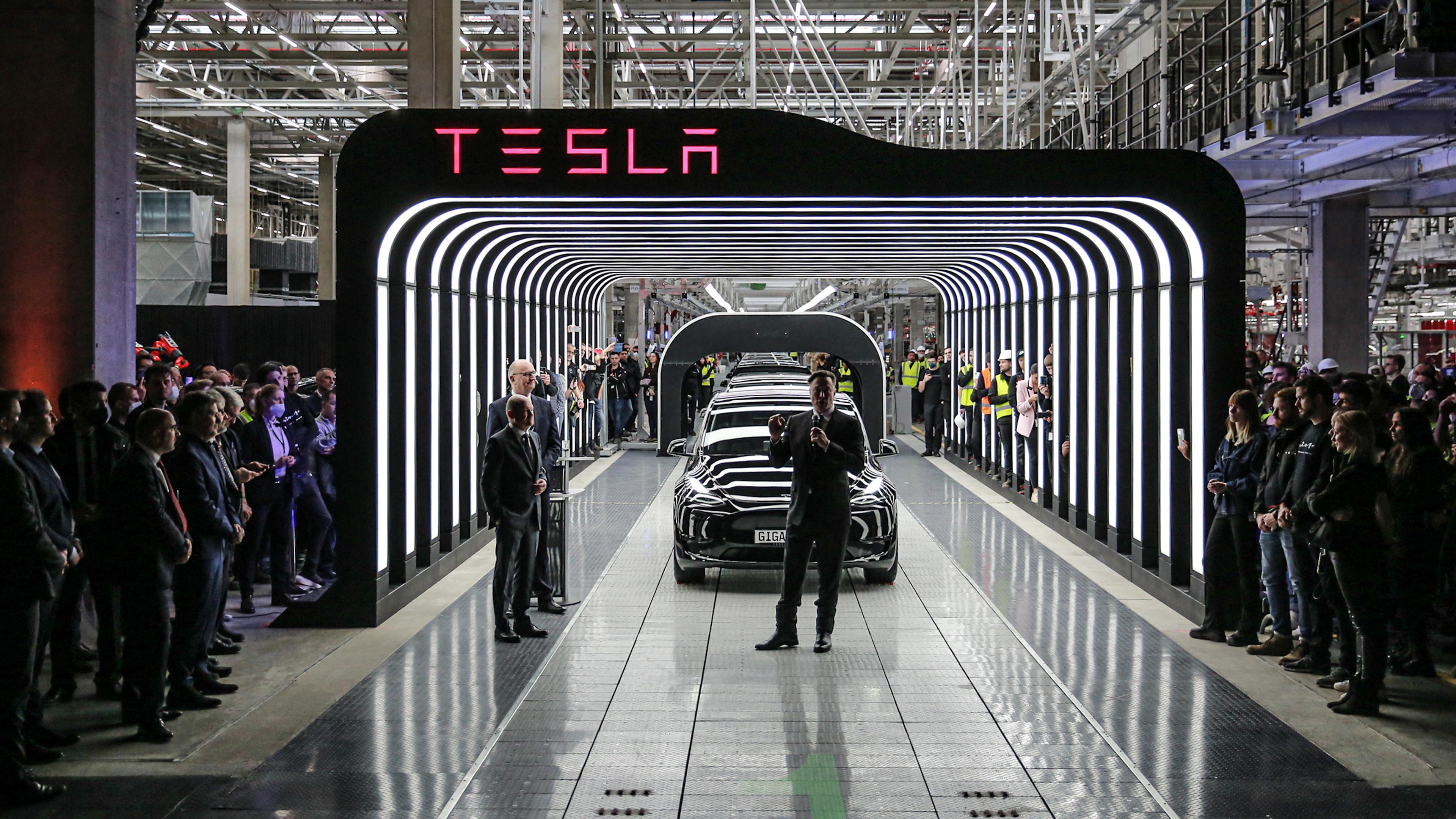 Tesla-CEO Elon Musk (M.) hält neben Brandenburgs Ministerpräsident Dietmar Woidke (2. v. l.) und Bundeskanzler Olaf Scholz (l.) am Eröffnungstag der Tesla-Gigafactory in Grünheide bei Berlin, Deutschland, am 22. März 2022 eine Rede.