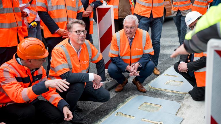 Markus Blume (CSU, 2.v.l), Bayerischer Wissenschaftsminister, und Joachim Herrmann (CSU, M), Bayerischer Innenminister, lassen sich die Funktionsweise des induktiven Ladens auf der A6 erklären. 