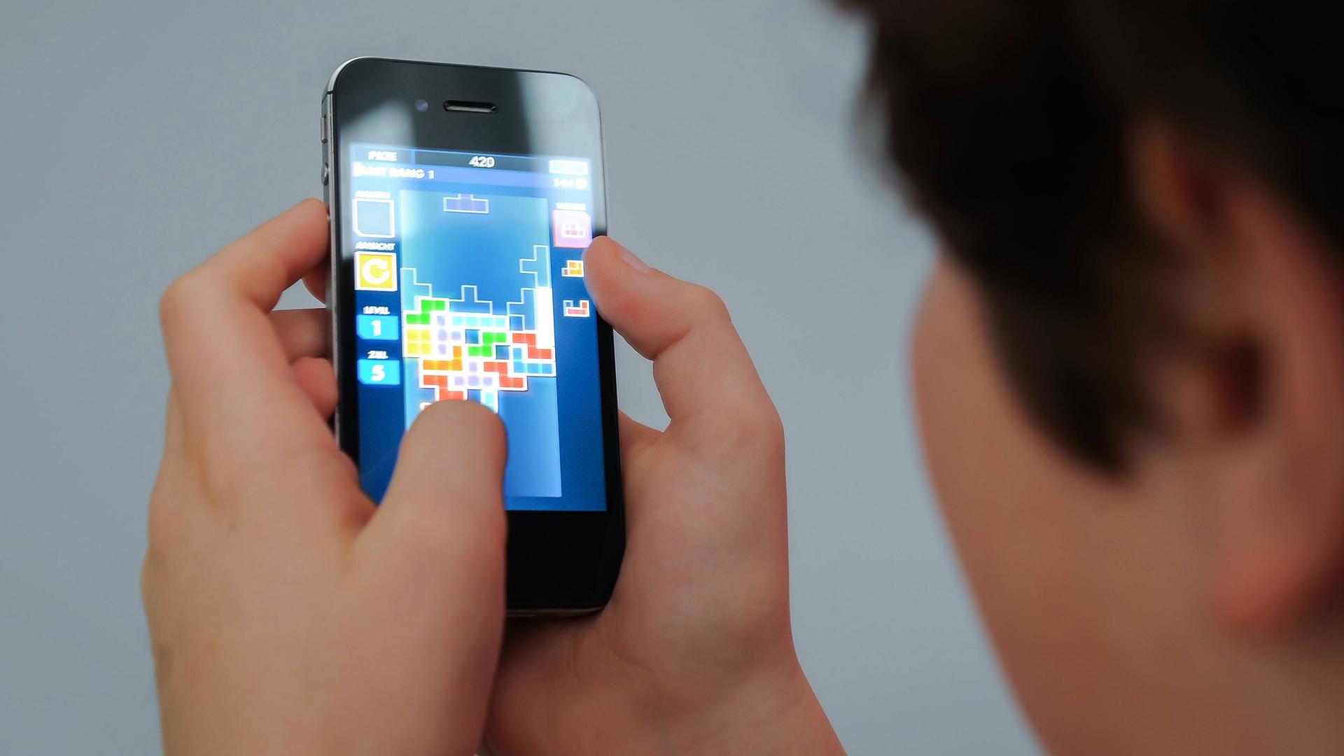 Ein Kind benutzt ein Smartphone und spielt das Spiel Tetris