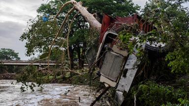 Ein Lkw liegt zerstört neben einem Fluss. Ein Baum steckt in den Fahrzeug