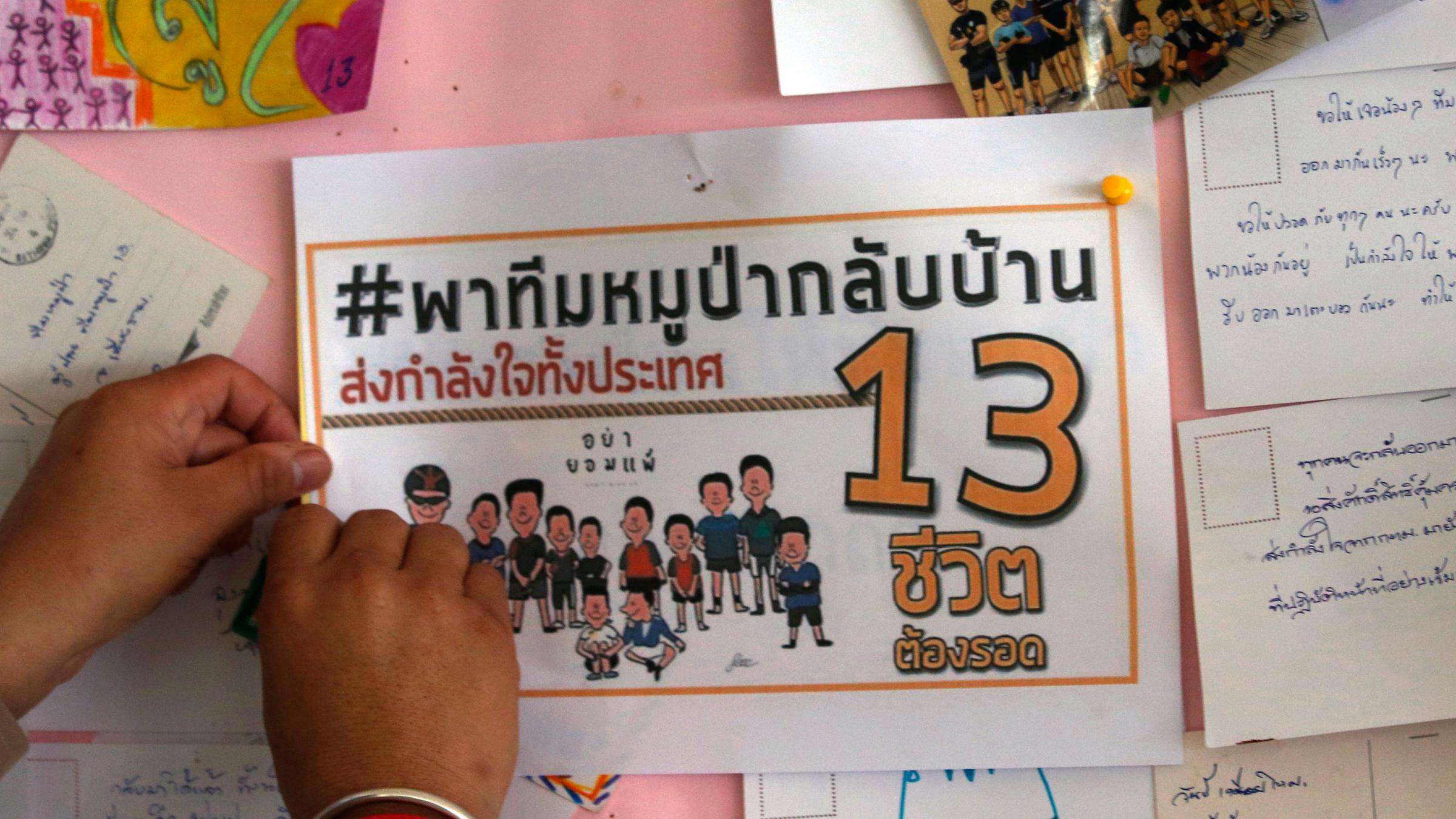 Ein Schulkind pinnt ein Gebet für die eingeschlossenen Jugendlichen an eine Wand