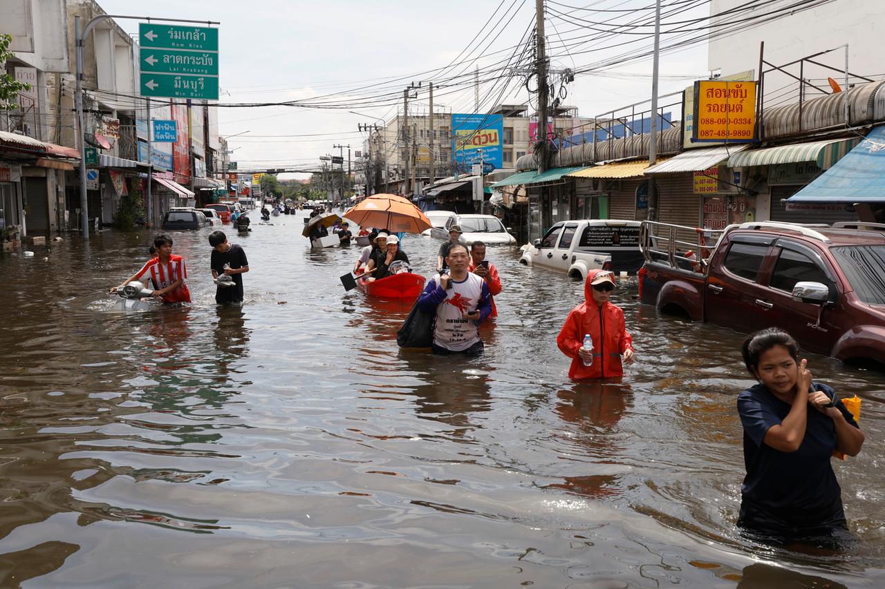 Bewohner waten durch das Hochwasser, um in der überfluteten Wohnsiedlung Rom Klao im Bangkoker Stadtteil Lat Krabang Lebensmittel und Güter des täglichen Bedarfs zu holen.