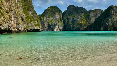 Eine Meeresbucht in Thailand, umgeben von bewachsenen Felsen.