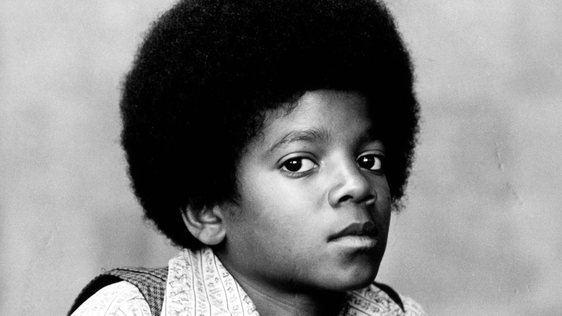  Schwarz-weißes Portraitfoto von Michael Jackson als Kind. Er blickt mit offenen Augen in die Kamera.