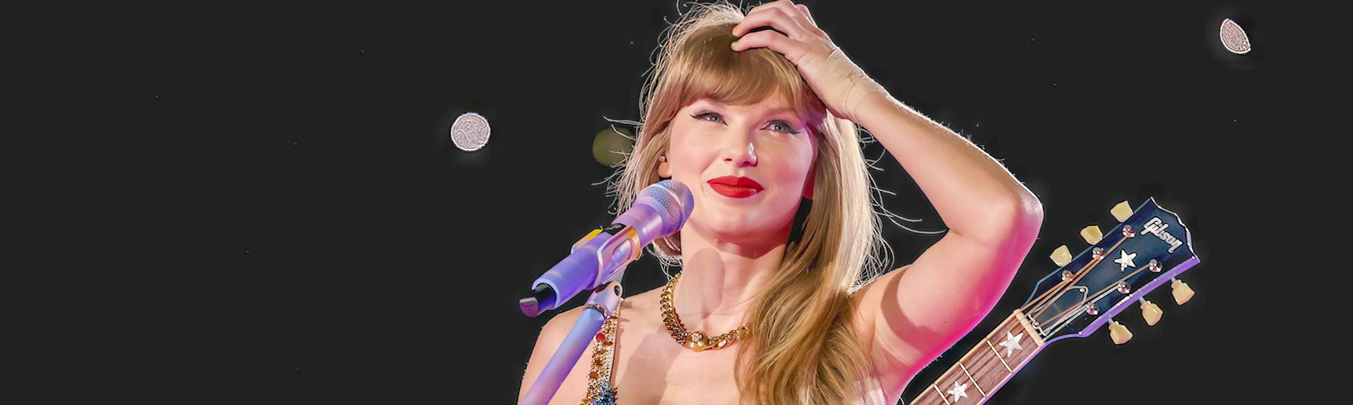 Taylor Swift steht mit Gitarre an einem Mikrofon. Sie lächelt und fasst sich an den Kopf.