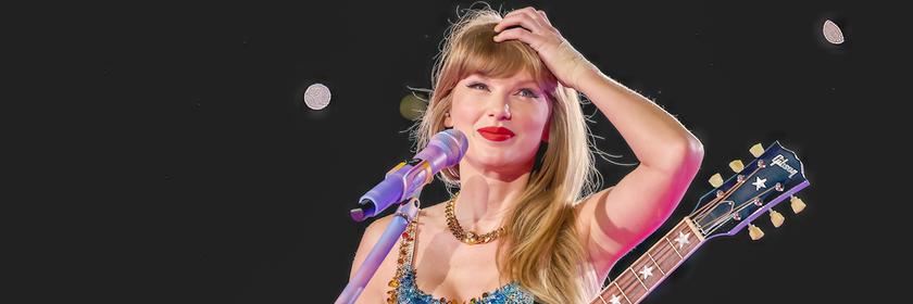 Taylor Swift steht mit Gitarre an einem Mikrofon. Sie lächelt und fasst sich an den Kopf.