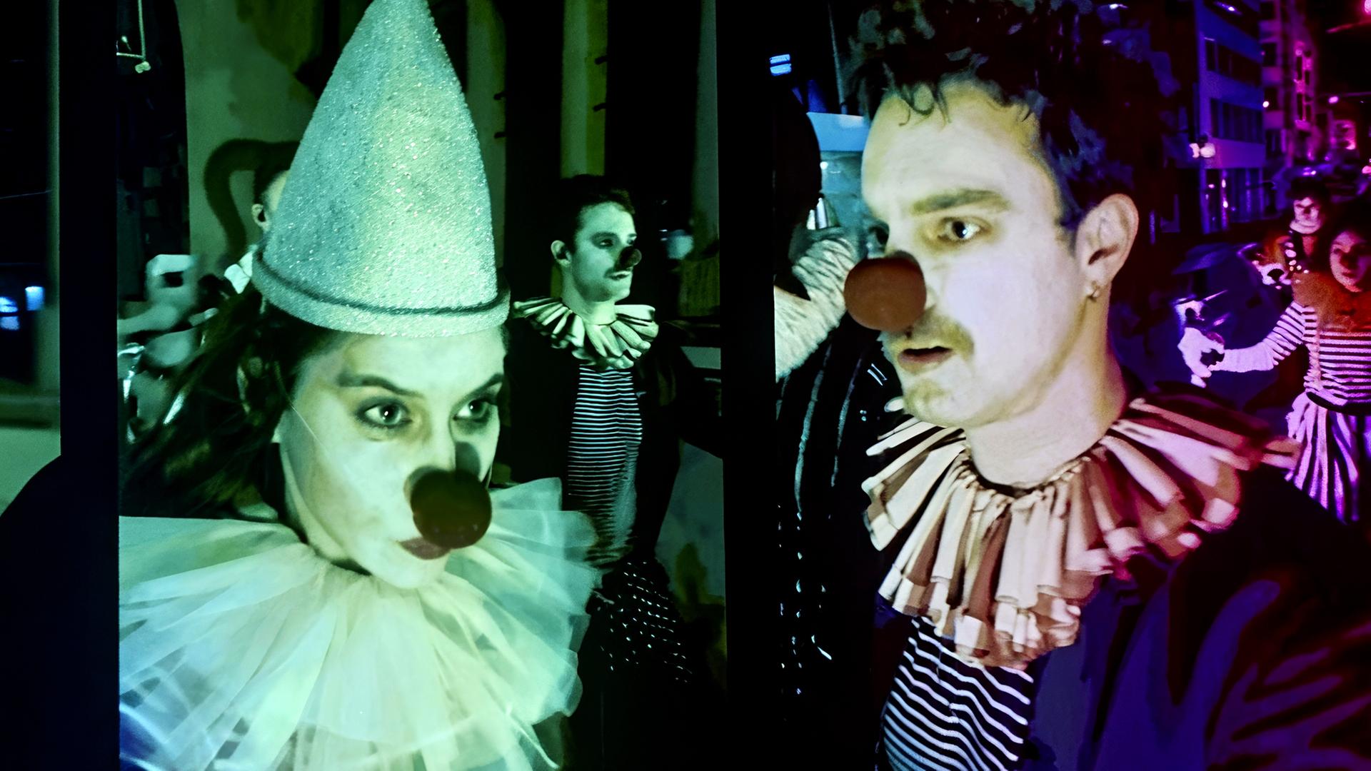Eine Frau und ein Mann haben sich als Harlekin und Clown verkleidet.