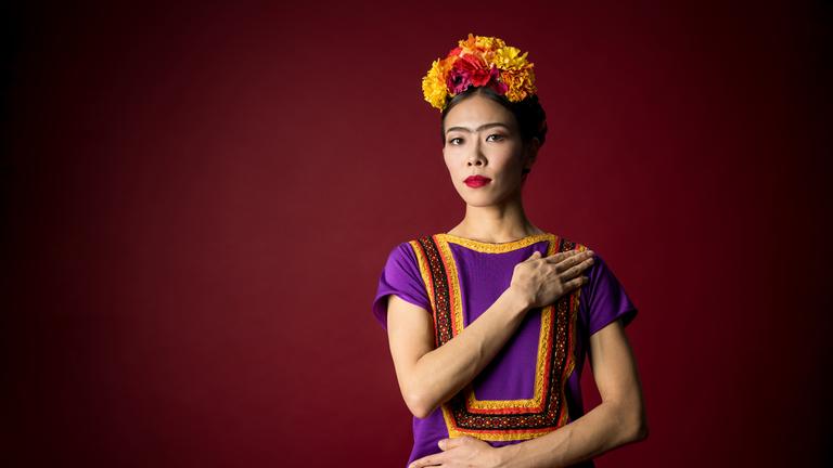 Man sieht eine Frau in folkloristisch, bunter Bekleidung.