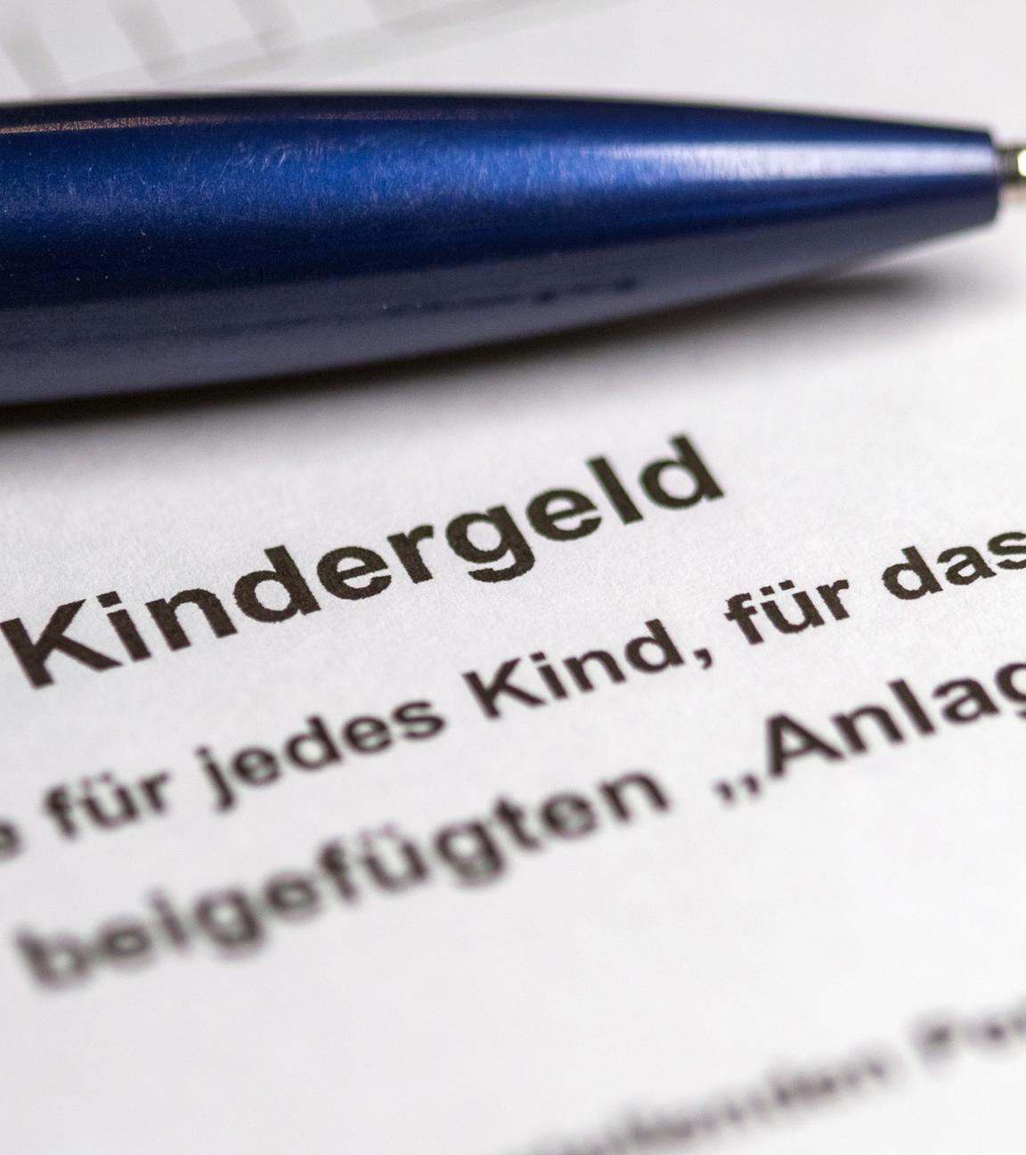 ein kugelschreiber liegt auf einem teilweise ausgefuellten antrag auf kindergeld.
