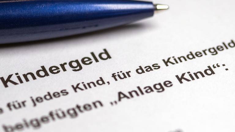 ein kugelschreiber liegt auf einem teilweise ausgefuellten antrag auf kindergeld.