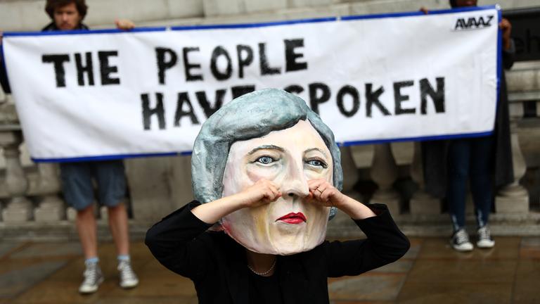 Demonstranten tragen eine Theresa May Maske, die weint.