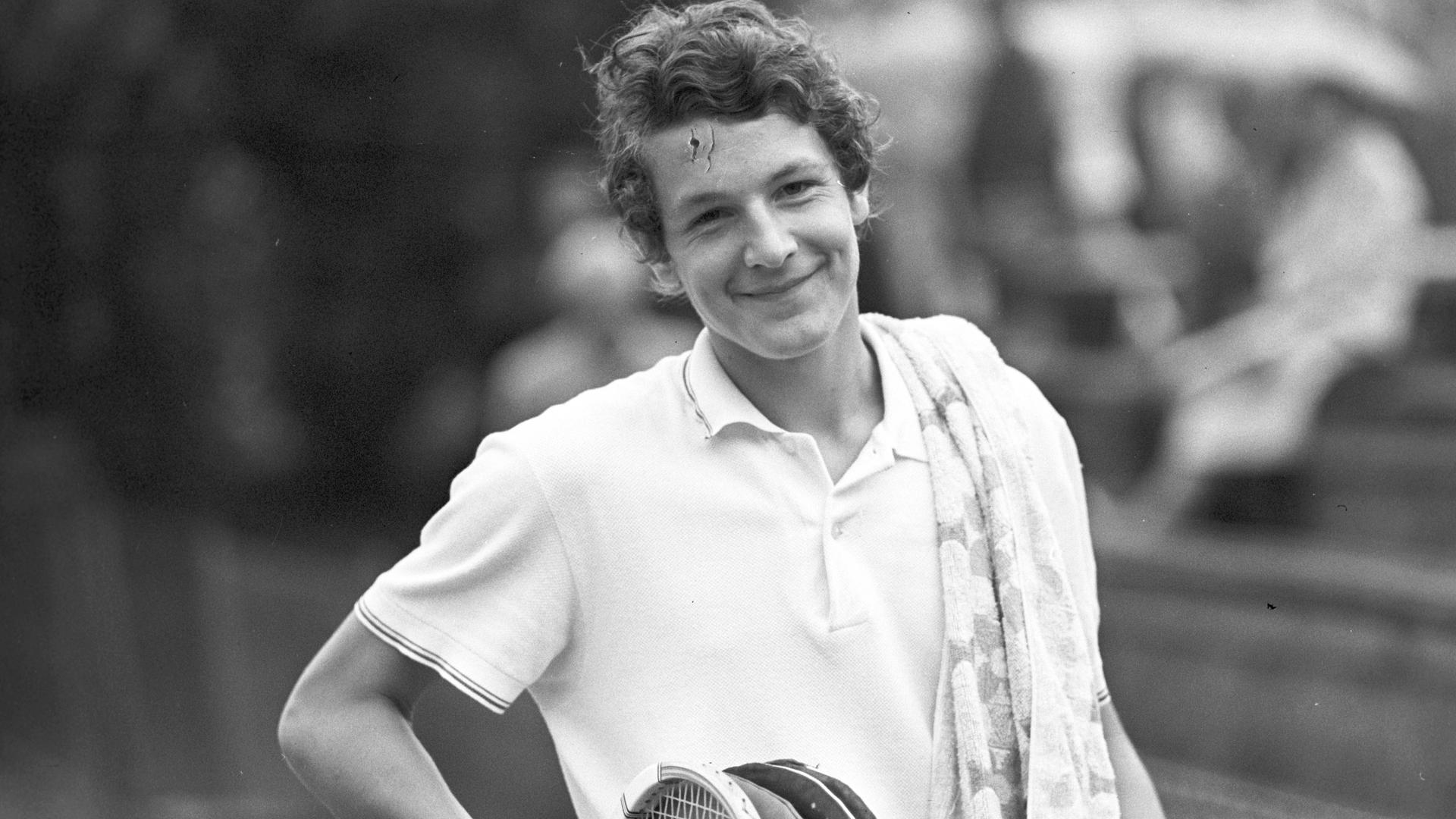 Tennisspieler Thomas Emmrich lächelnd, mit ein paar Tennisschlägern in der Hand.