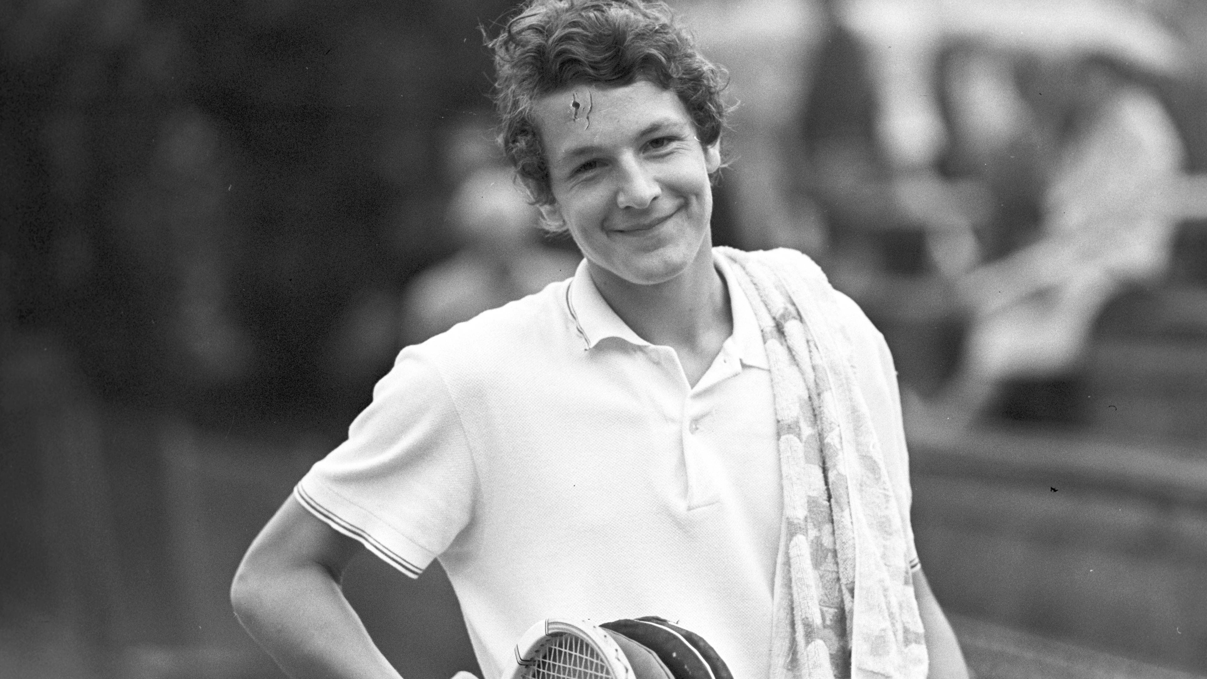Tennisspieler Thomas Emmrich lächelnd, mit ein paar Tennisschlägern in der Hand.
