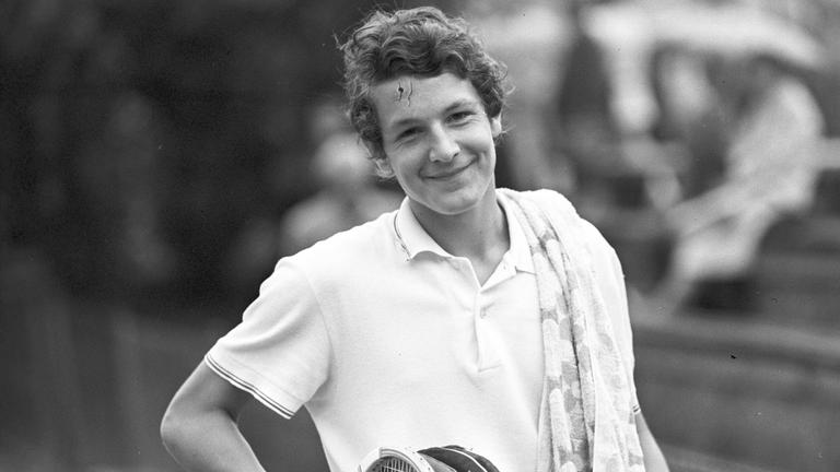 Tennisspieler Thomas Emmrich lächelnd, mit ein paar Tennisschlägern in der Hand.