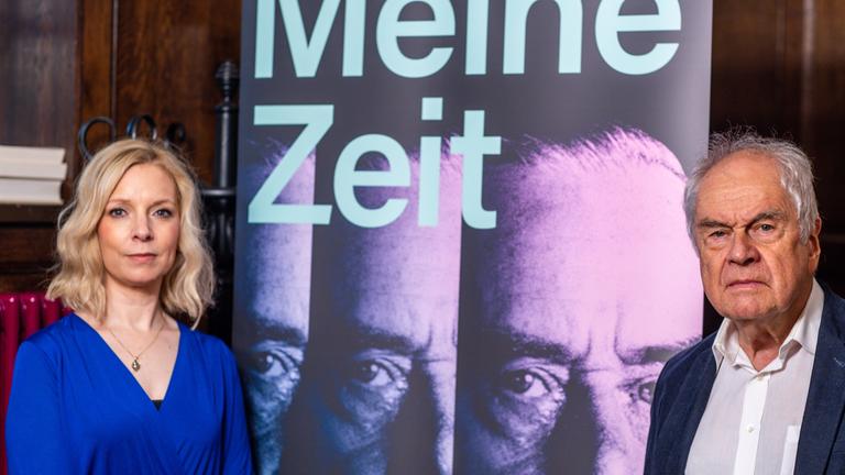 Frido Mann, der Enkel des Literaturnobelpreisträgers Thomas Mann, und Caren Heuer, die Direktorin des Buddenbrookhauses, stehen bei einem Fototermin vor dem Festakt der Stadt Lübeck zum 150. Geburtstag von Thomas Mann in der Aegidien Kirche neben einem Aussteller für die Sonderausstellung. Zum 150. Geburtstag von Thomas Mann gibt es einen Festakt und es wird die Ausstellung mit dem Titel «Meine Zeit. Thomas Mann und die Demokratie» des Buddenbrookhauses eröffnet.