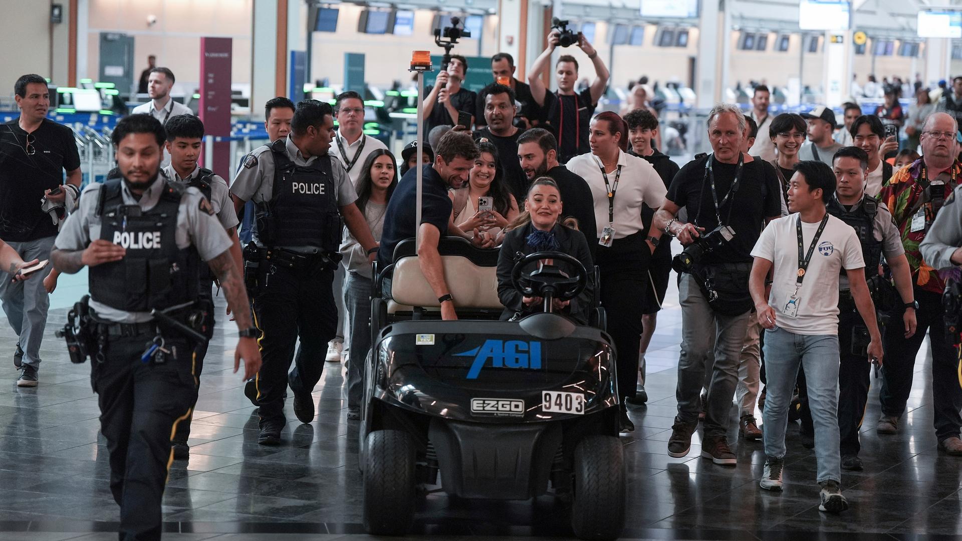 Der neue Spieler der Vancouver Whitecaps, Thomas Müller (M,l), wird in einem Golfwagen zu Fans gefahren, nachdem er aus Deutschland am Vancouver International Airport angekommen ist. 