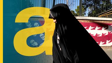 Iranische Frau läuft vor einer bemalten Wand mit Totenköpfen