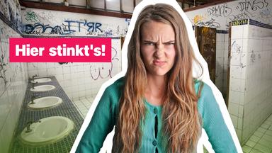 Ein Mädchen rümpft die Nase, im Hintergrund Schultoiletten