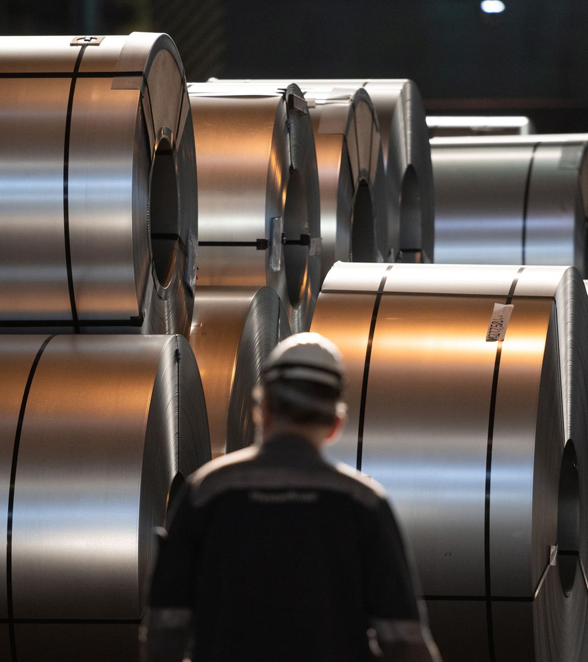 Ein Mitarbeiter von Thyssenkrupp geht im Duisburger Werk an aufgerolltem Stahl vorbei (Archiv)