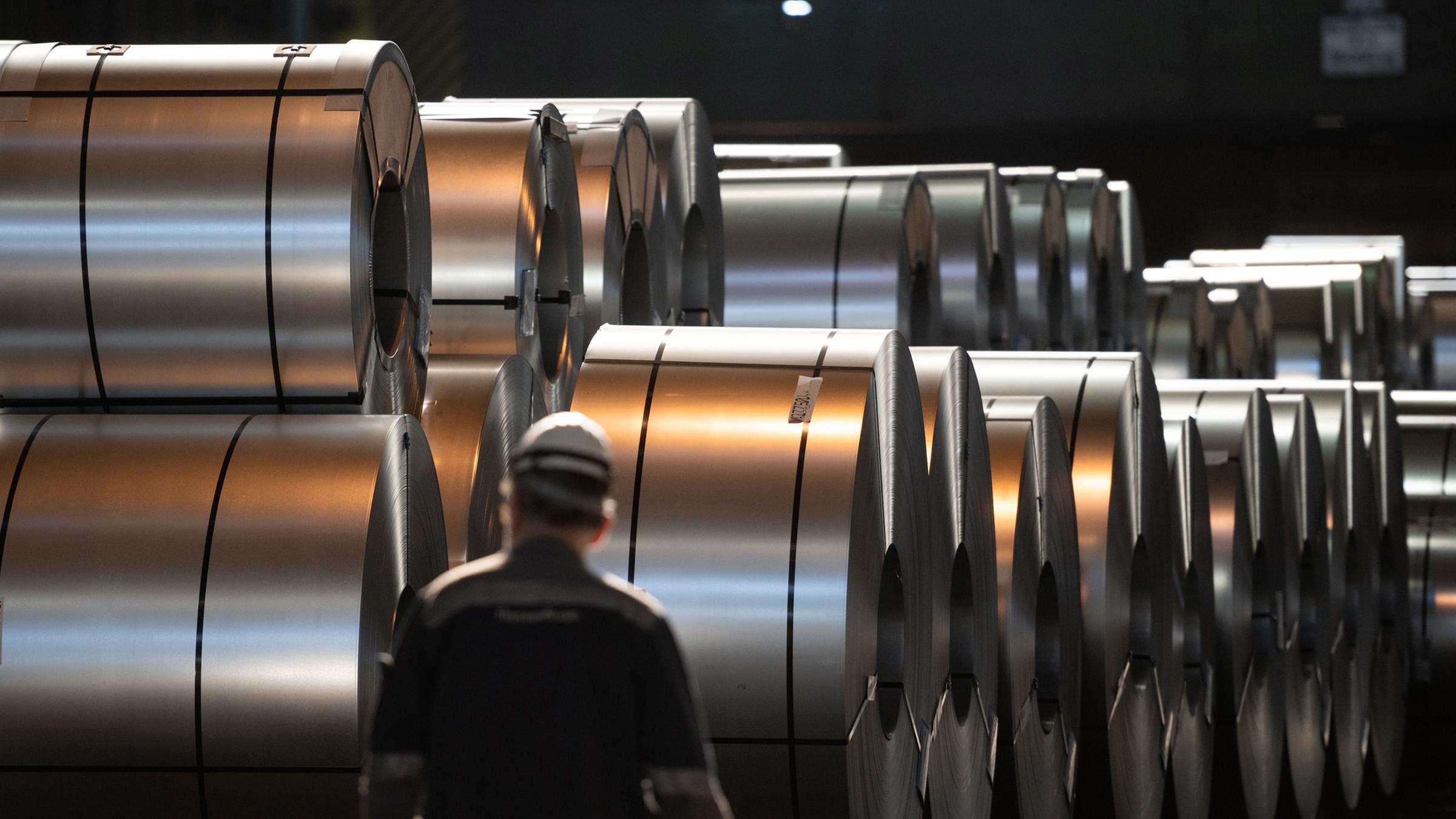 Ein Mitarbeiter von Thyssenkrupp geht im Duisburger Werk an aufgerolltem Stahl vorbei (Archiv)