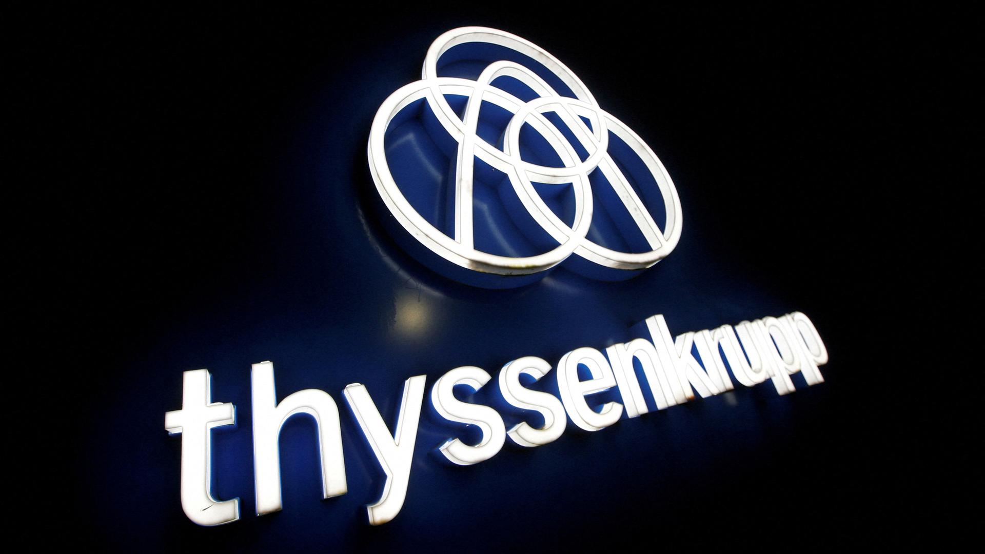 Das Thyssenkrupp Logo und Schriftzug in leuchtenden Buchstaben auf schwarzem Untergr
