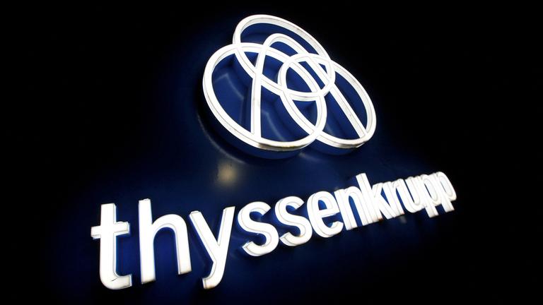 Das Thyssenkrupp Logo und Schriftzug in leuchtenden Buchstaben auf schwarzem Untergr