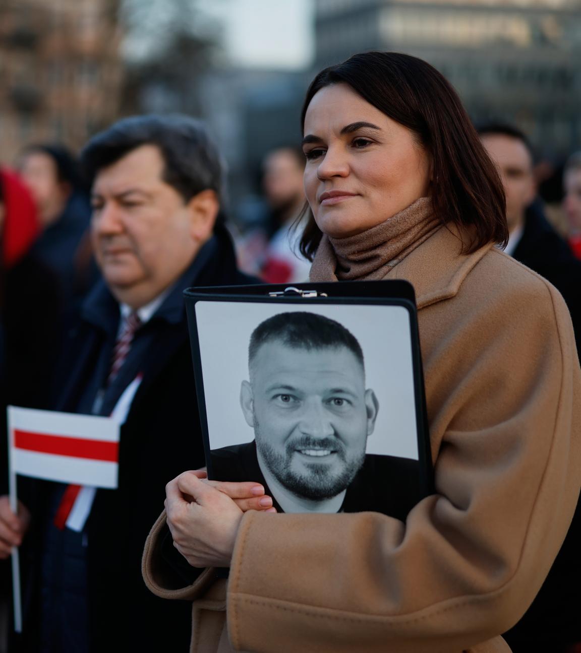 Belarussiche Oppositionsführerin Tichanowskaja hält Foto ihres Ehemanns während Feierlichkeit.