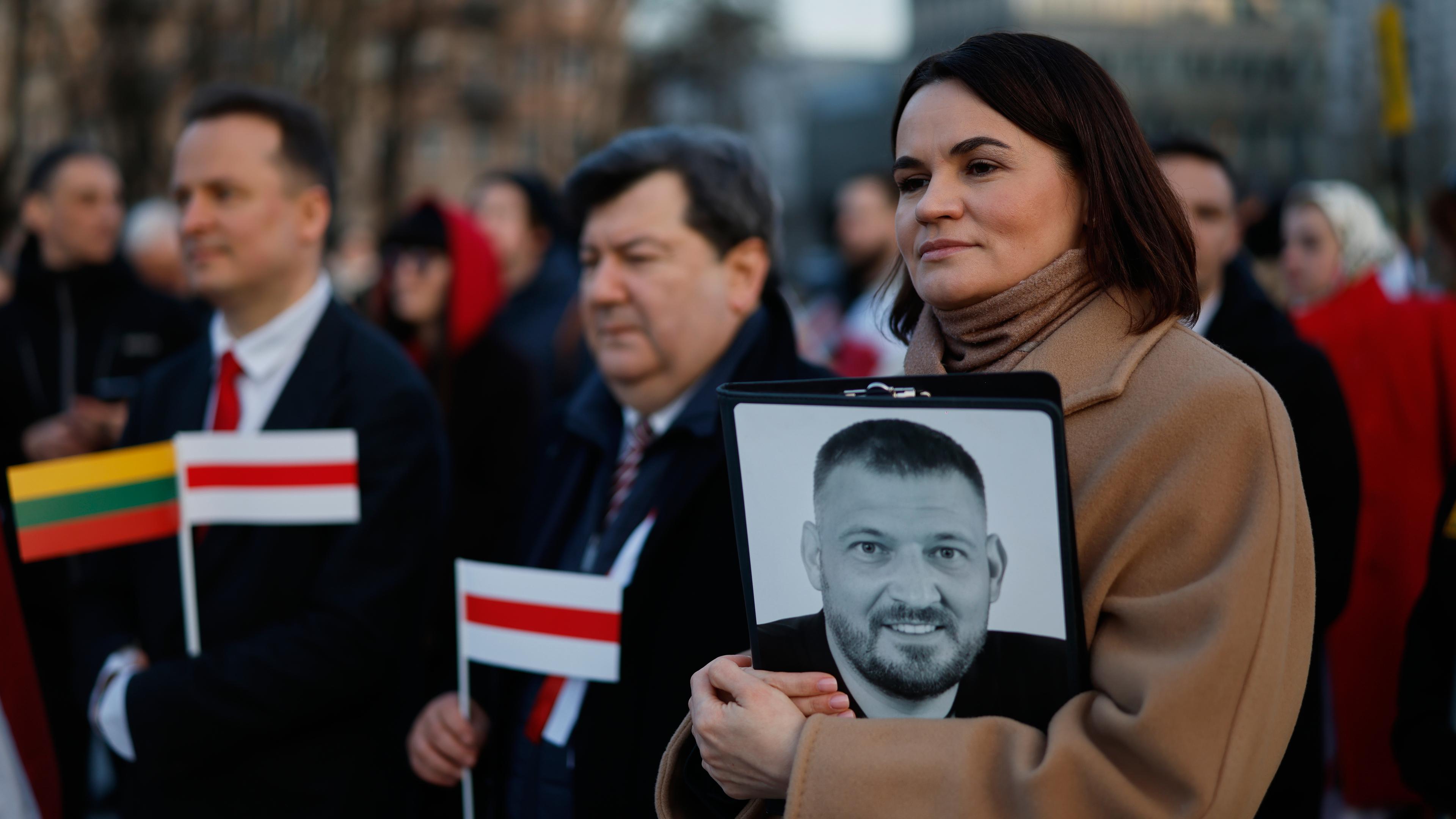Belarussiche Oppositionsführerin Tichanowskaja hält Foto ihres Ehemanns während Feierlichkeit.