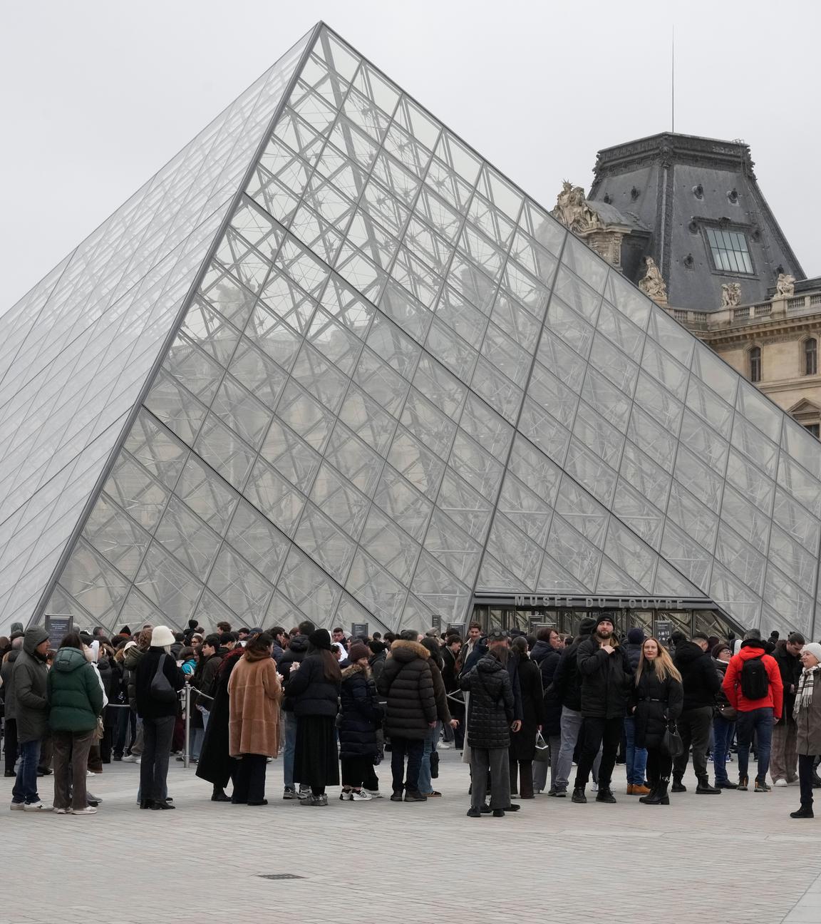 Frankreich, Paris: Eine Menschenschlange steht vor dem Louvre-Museum an der gläsernen Pyramide.