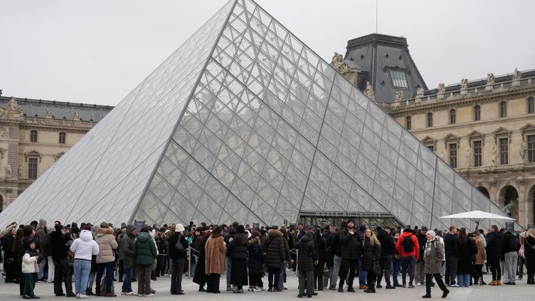 Frankreich, Paris: Eine Menschenschlange steht vor dem Louvre-Museum an der gläsernen Pyramide.