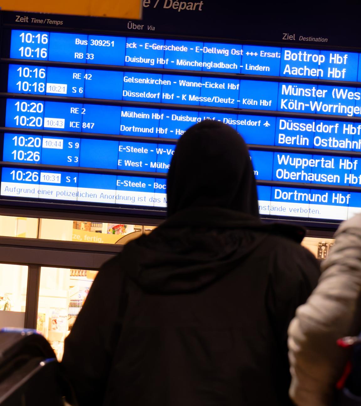 Reisende betrachten im Hauptbahnhof eine Anzeigetafel, um sich am neuen Fahrplan der Deutschen Bahn zu orientieren.