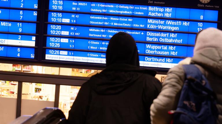 Reisende betrachten im Hauptbahnhof eine Anzeigetafel, um sich am neuen Fahrplan der Deutschen Bahn zu orientieren.