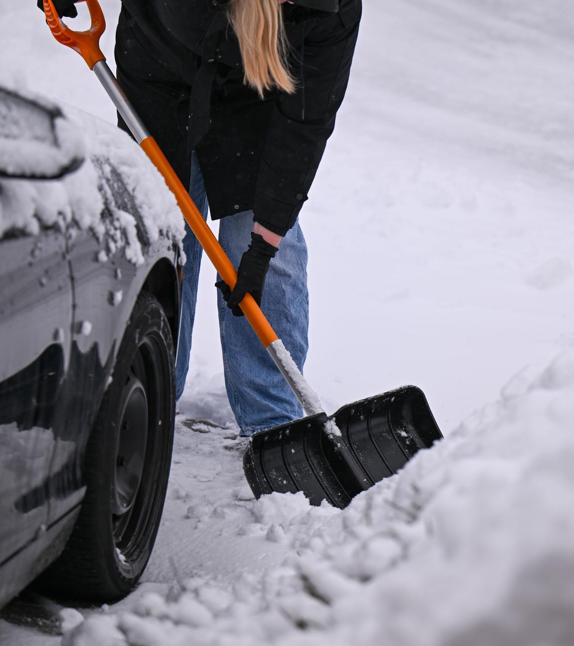 Eine Frau beseitigt Schnee von einem Bürgersteig