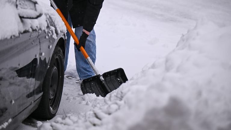 Eine Frau beseitigt Schnee von einem Bürgersteig