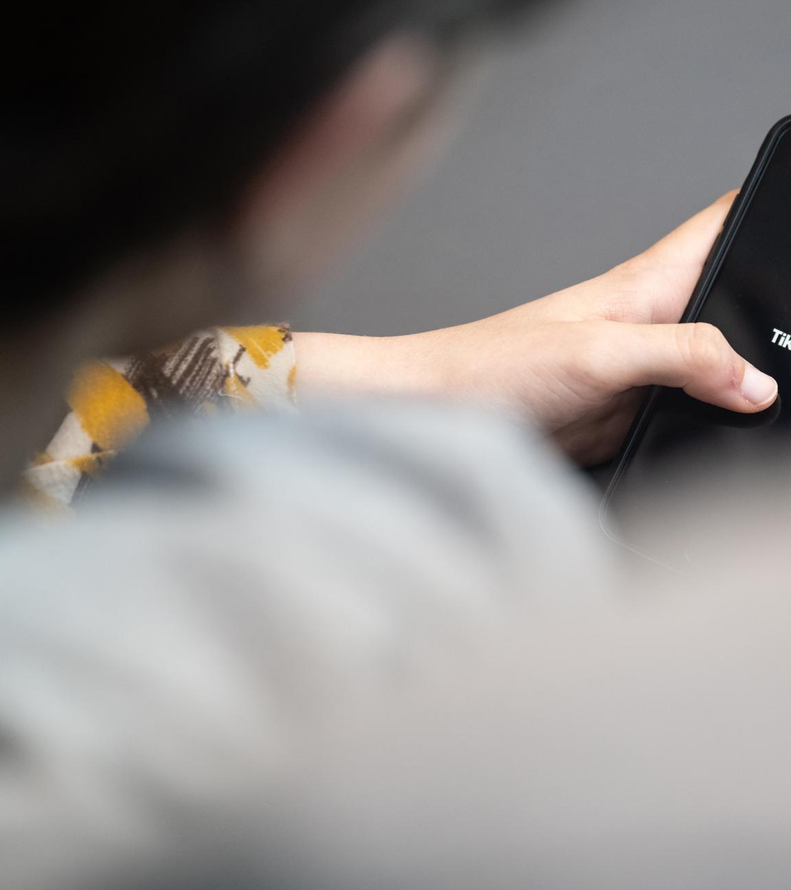 Frau öffnet die App TikTok auf ihrem Handy