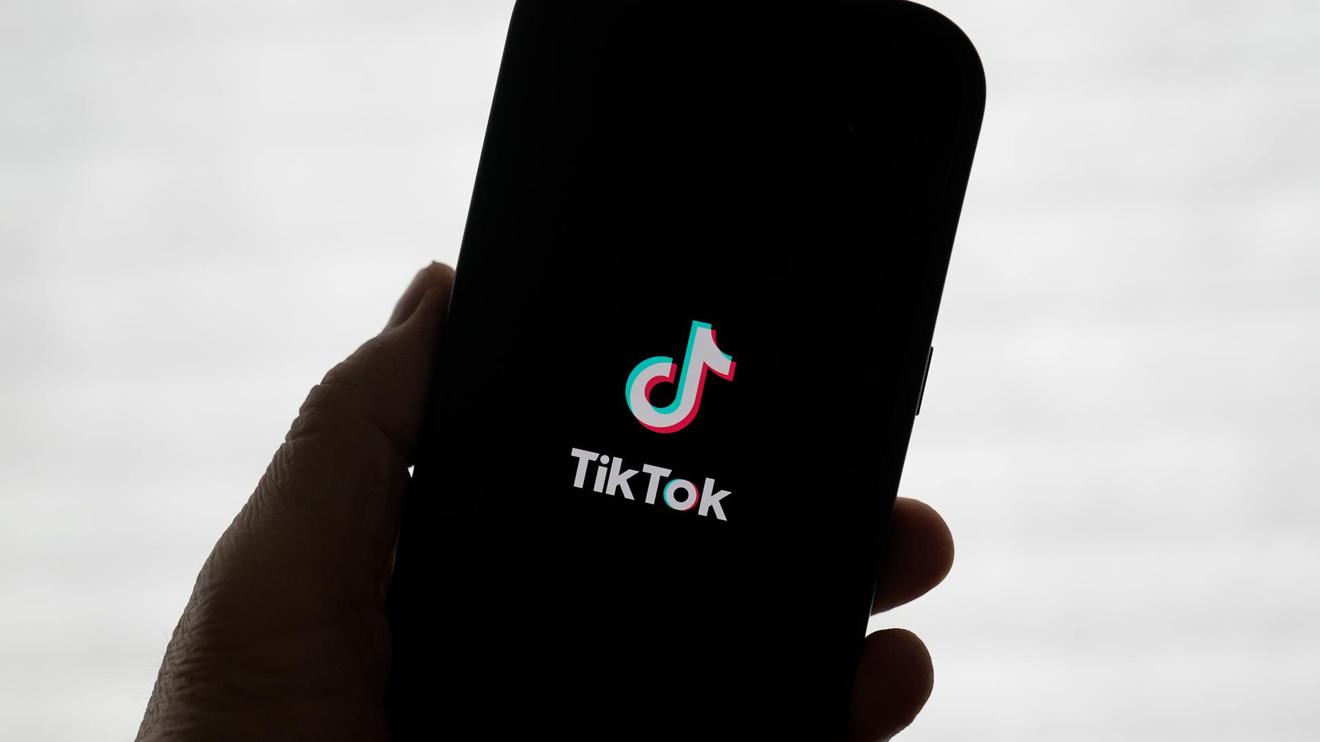 TikTok auf einen Smartphone das in einer Hand gehalten wird