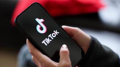 Ein Mädchen hält ein iPhone 16 in den Händen, auf dem das Logo der App TikTok zu sehen ist