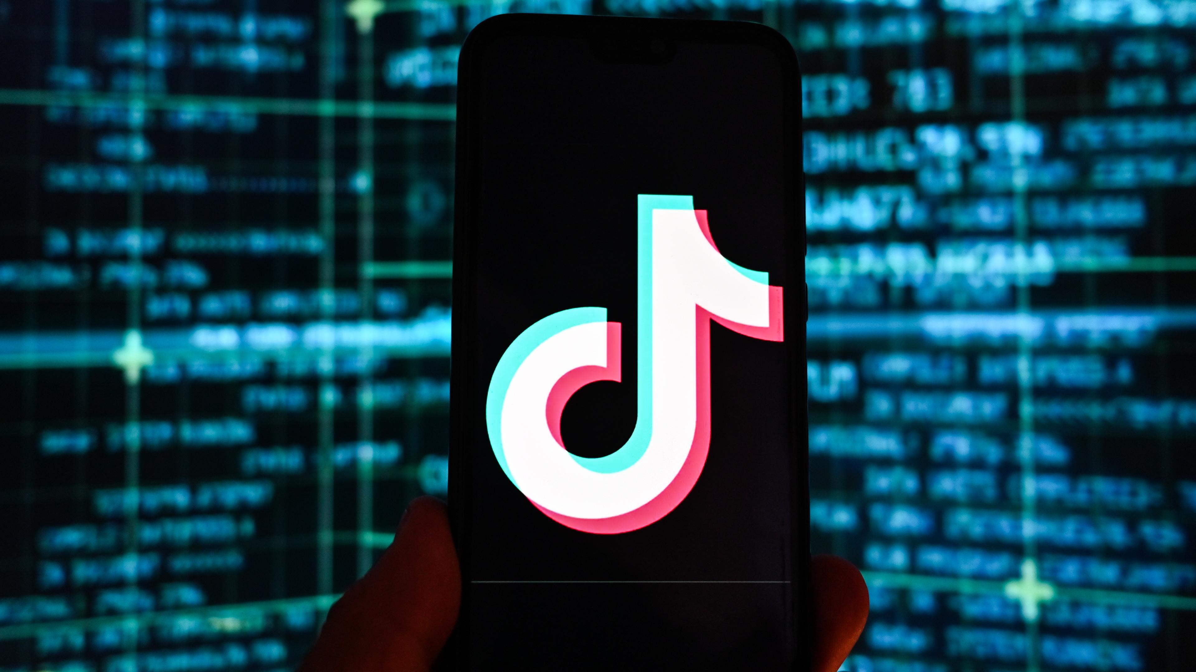 Ein Smartphone mit einem eingeblendeten TikTok-Logo vor einem Bildschirm.
