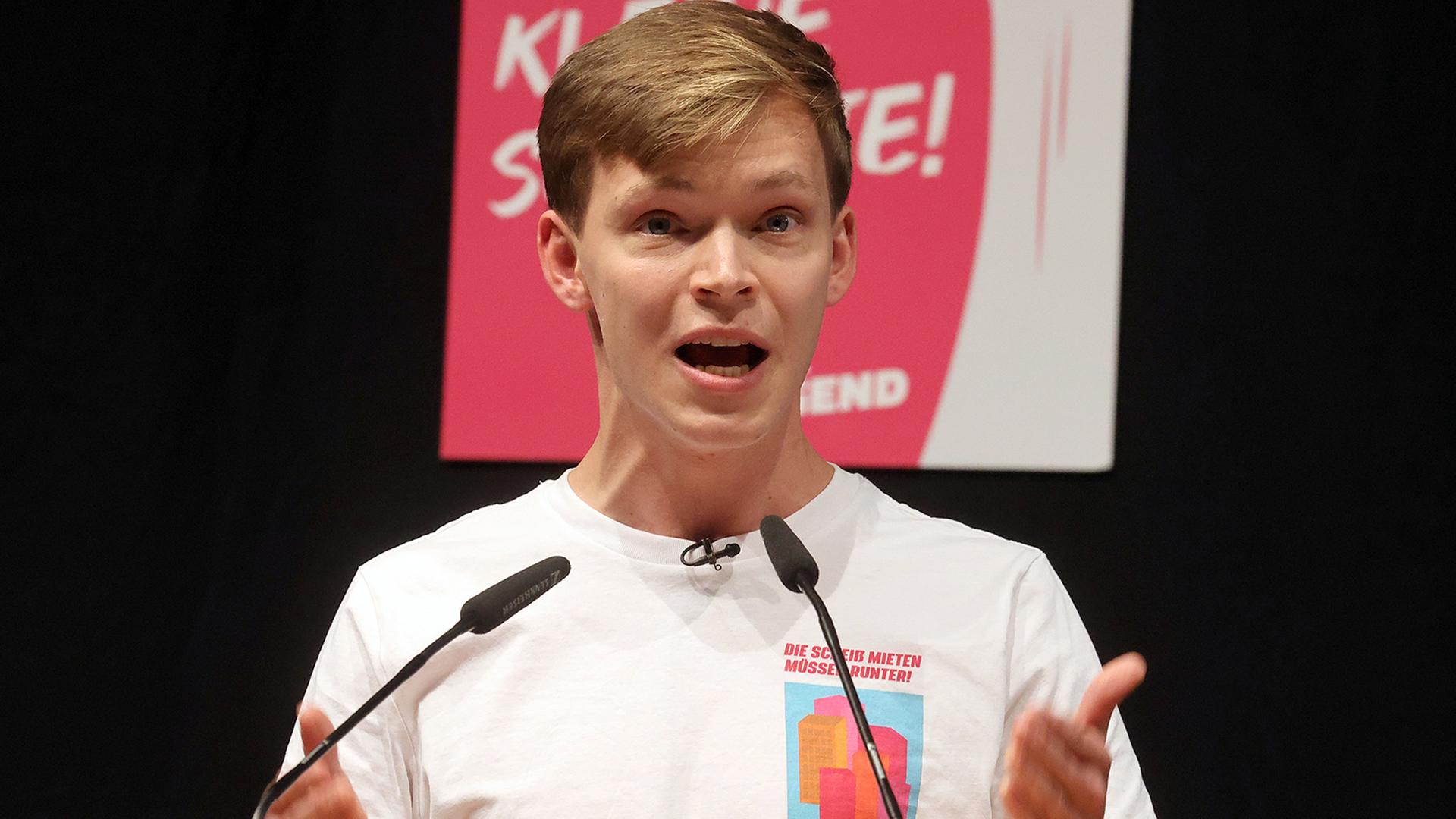 Timon Dzienus steht an einem Rednerpult und gestikuliert